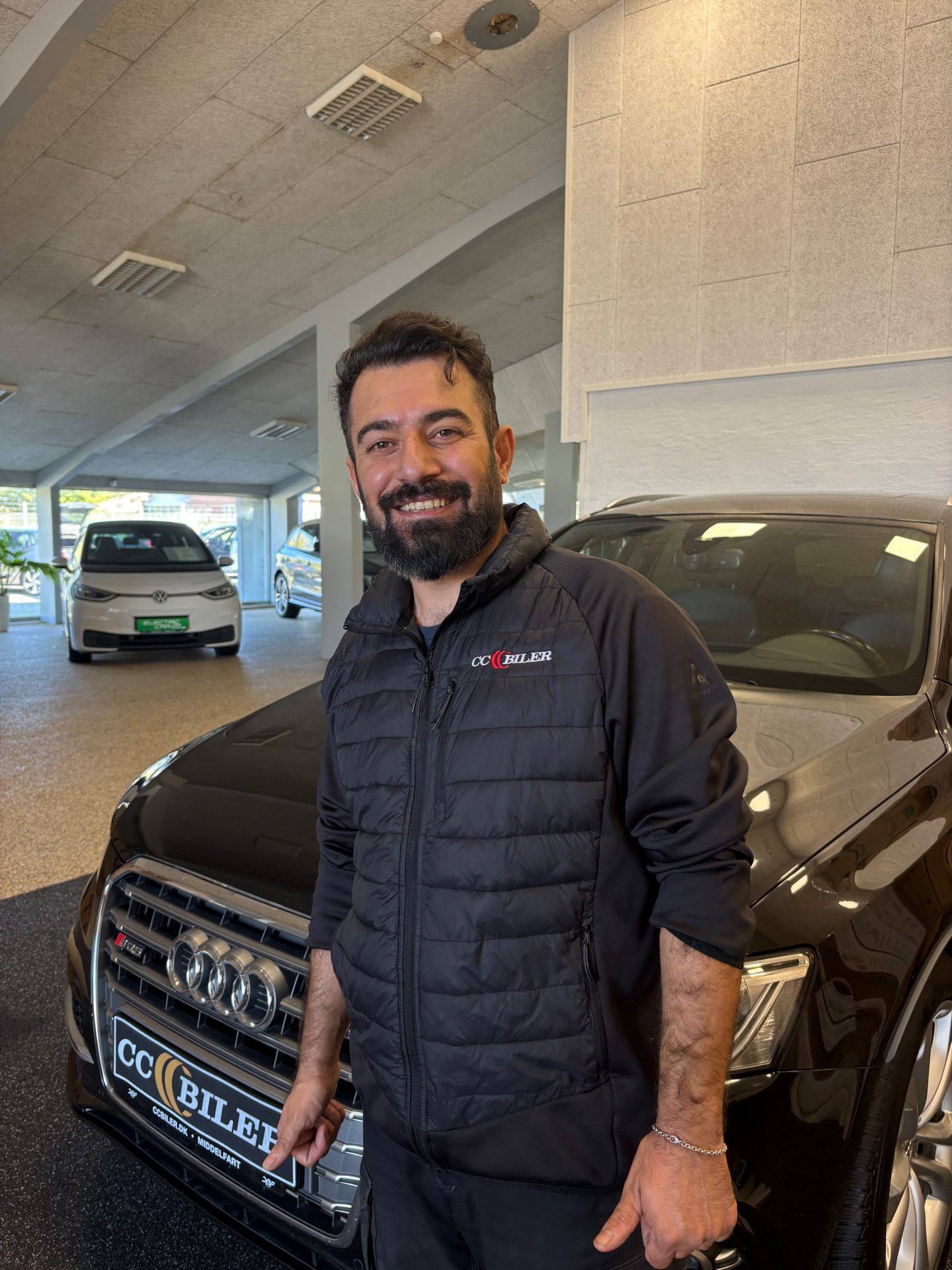 Osman Ramani, klargøringschef hos CC Biler, i CC Biler-jakke foran en sort Audi