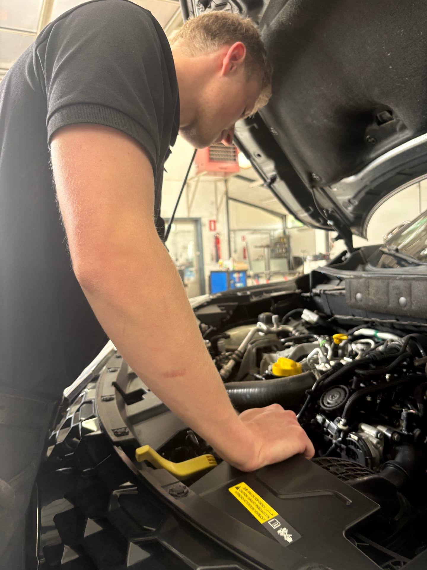 Mekaniker arbejder på en motor i værkstedet hos CC Biler