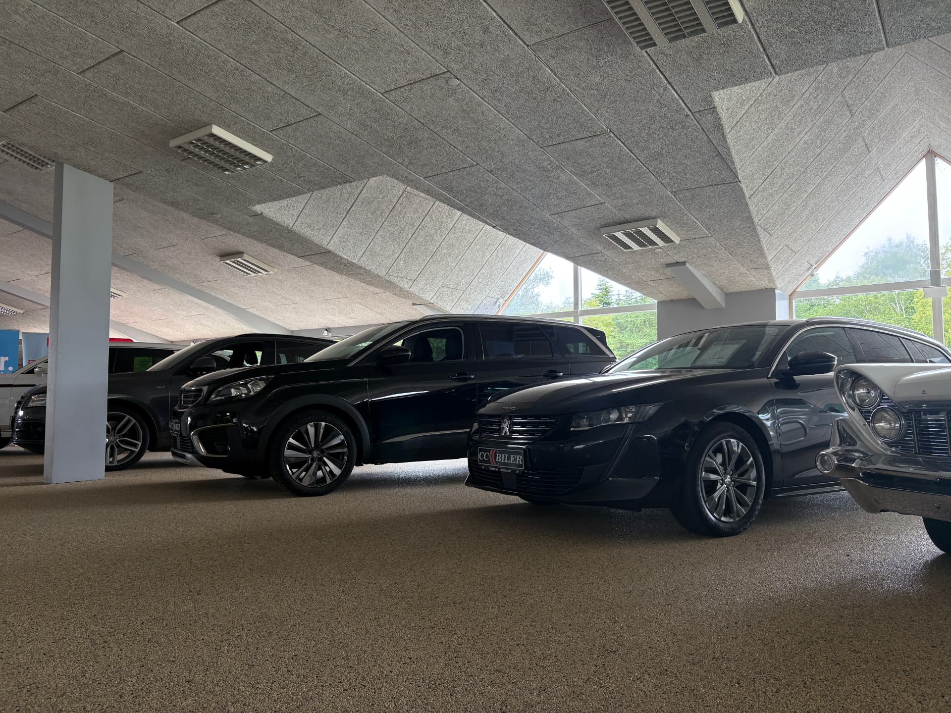 Række af brugte biler i CC Bilers indendørs showroom i Middelfart